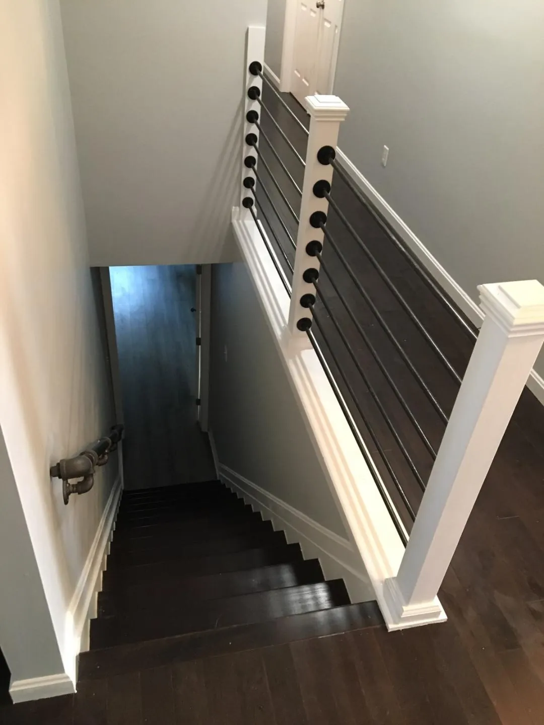 Basement stairway with white trim and cable railing