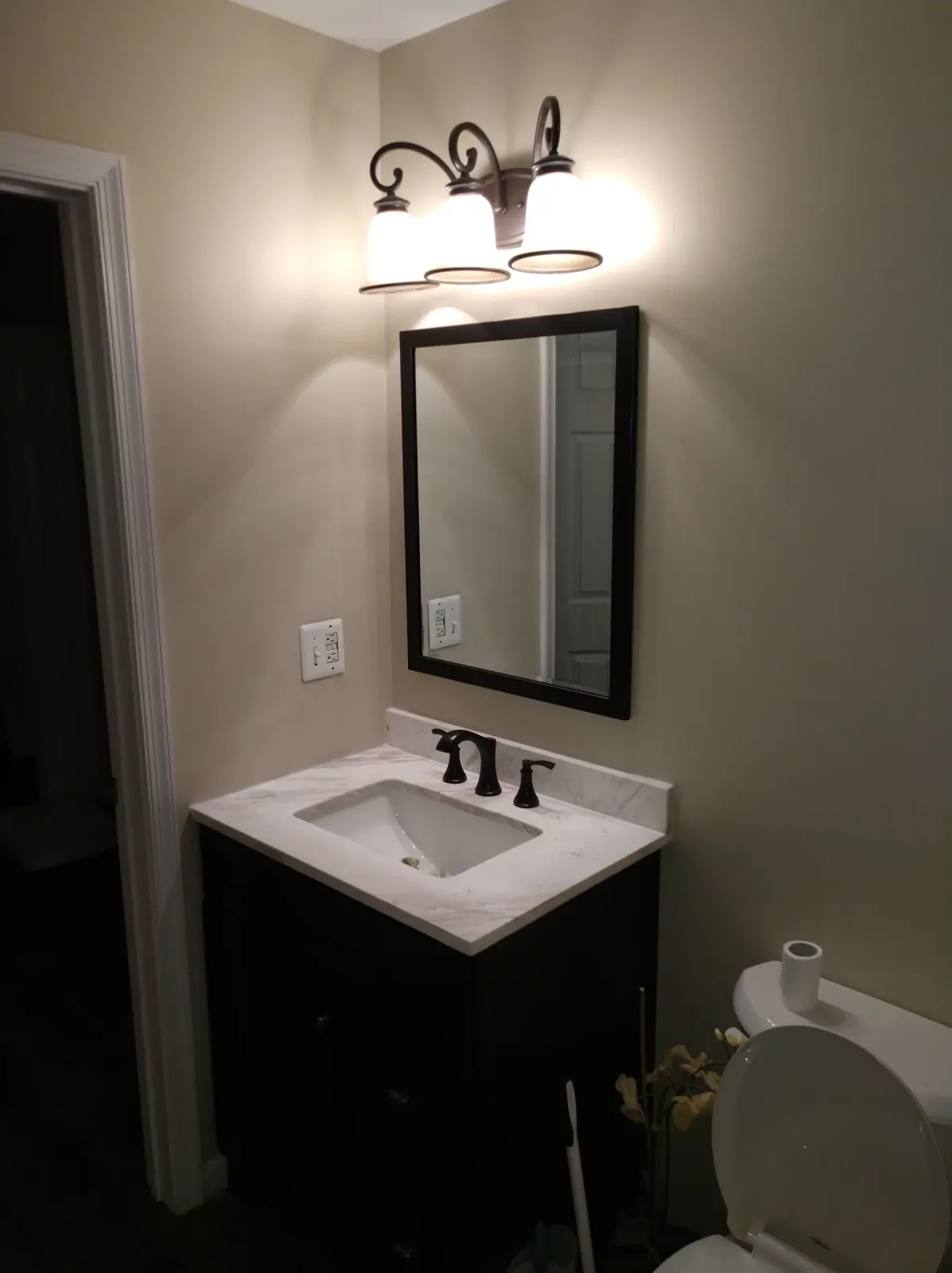Remodeled bathroom with dark vanity, white countertop and framed mirror