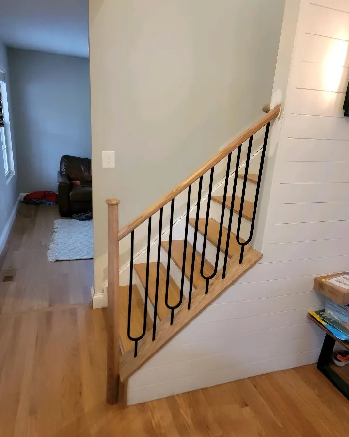 Stair railing with oak handrail and black iron balusters